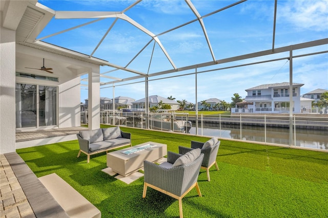 sunroom featuring ceiling fan and a water view