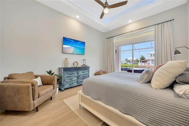 bedroom featuring ceiling fan, a tray ceiling, and light hardwood / wood-style flooring