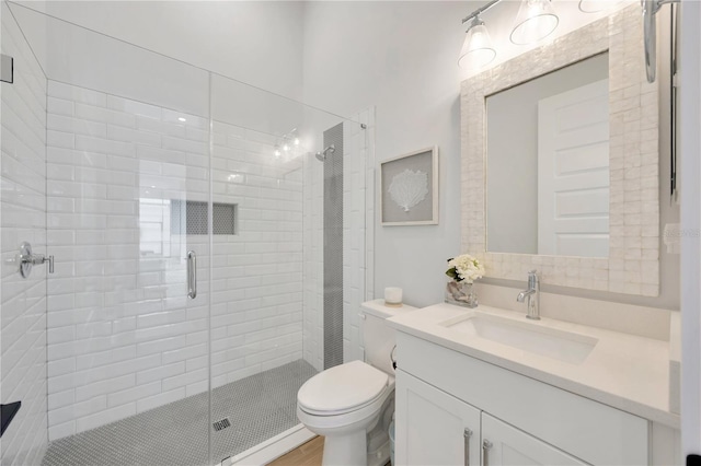 bathroom with vanity, a shower with shower door, and toilet