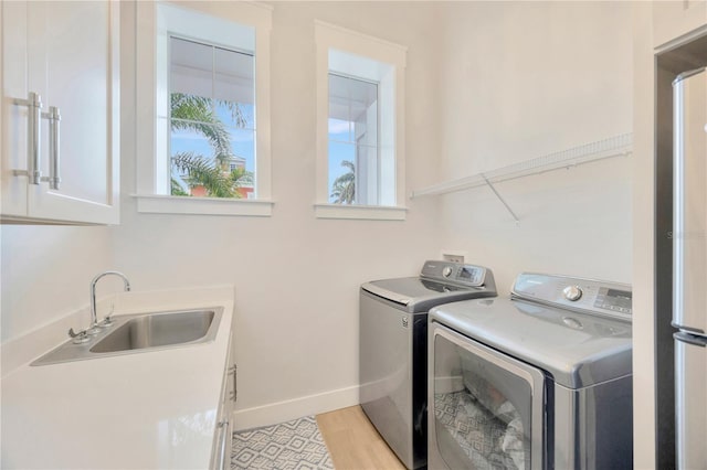 clothes washing area featuring cabinets, washer and clothes dryer, and sink