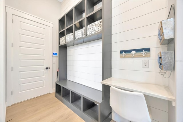 mudroom with built in desk and light hardwood / wood-style flooring