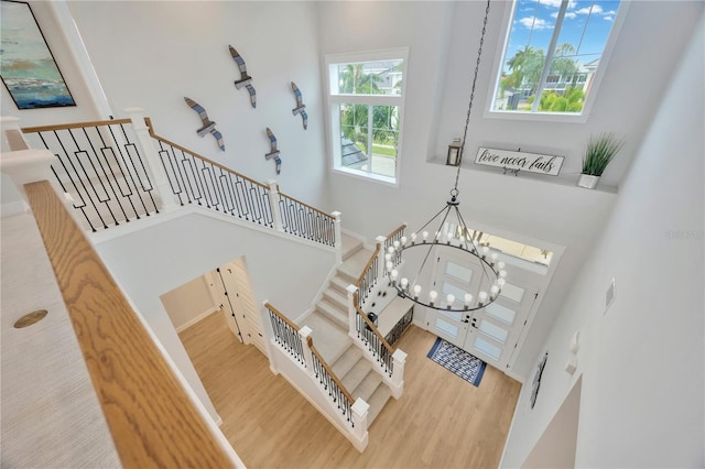 stairway featuring a towering ceiling, hardwood / wood-style floors, and a notable chandelier