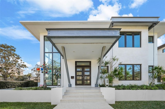 view of exterior entry featuring french doors and stucco siding