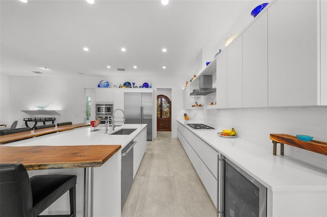 kitchen featuring light countertops, beverage cooler, white cabinetry, and a large island with sink