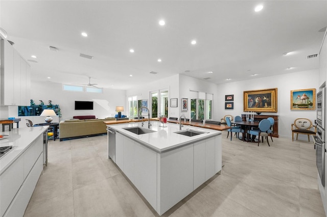 kitchen featuring white cabinetry, ceiling fan, sink, and an island with sink