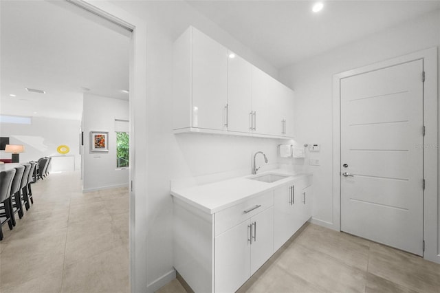 kitchen featuring light tile patterned floors, sink, and white cabinets