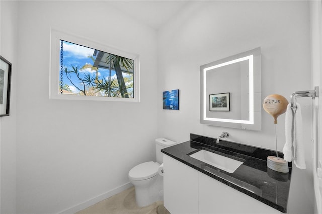 half bath featuring toilet, baseboards, and vanity