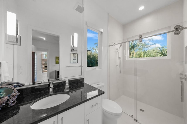 bathroom featuring a shower with door, vanity, and toilet