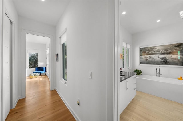 hall with light wood-type flooring, baseboards, and recessed lighting