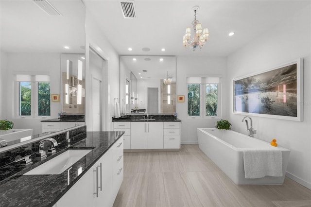 bathroom featuring a freestanding bath, visible vents, two vanities, and a sink