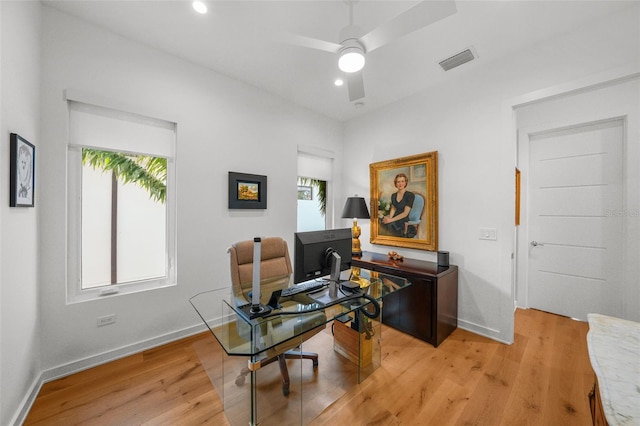 office featuring baseboards, light wood-type flooring, visible vents, and a healthy amount of sunlight