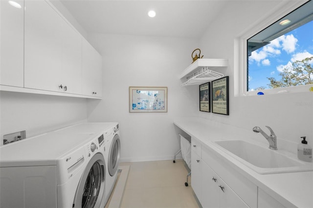 clothes washing area with separate washer and dryer, a sink, cabinet space, and baseboards