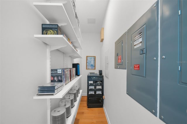 hallway featuring electric panel, baseboards, and wood finished floors