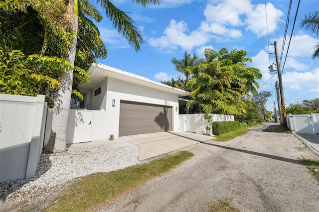 view of front facade with fence, driveway, an attached garage, and stucco siding