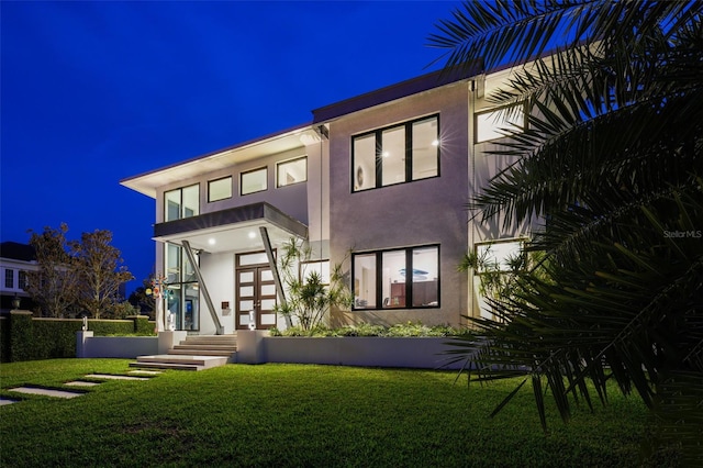 back of property featuring a yard and stucco siding