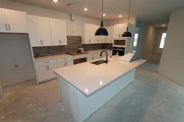 kitchen with an island with sink, a sink, black appliances, white cabinets, and backsplash