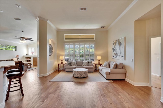 living room with light wood-type flooring, ornamental molding, and ceiling fan