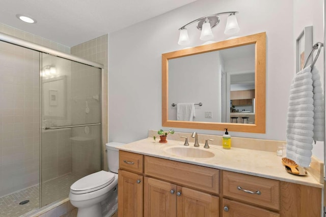 bathroom featuring vanity, a shower with shower door, and toilet