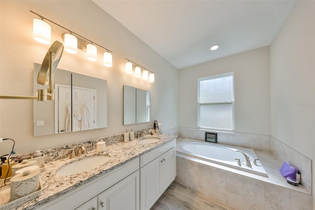 bathroom featuring a relaxing tiled tub and vanity