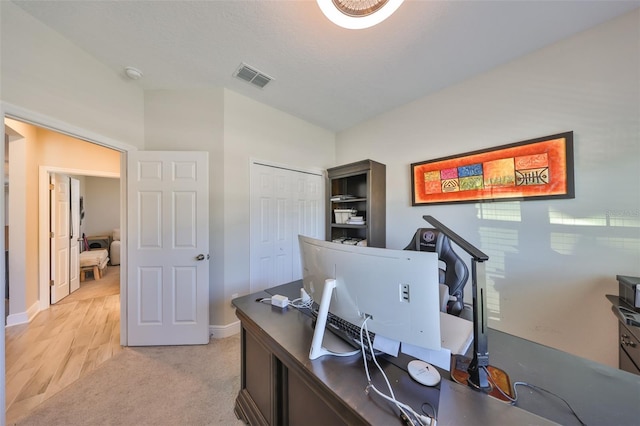 home office featuring light colored carpet, visible vents, and baseboards