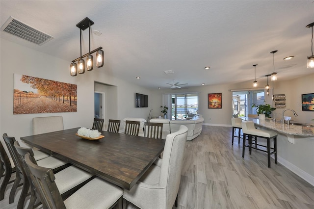 dining area with light wood-style flooring, visible vents, and baseboards