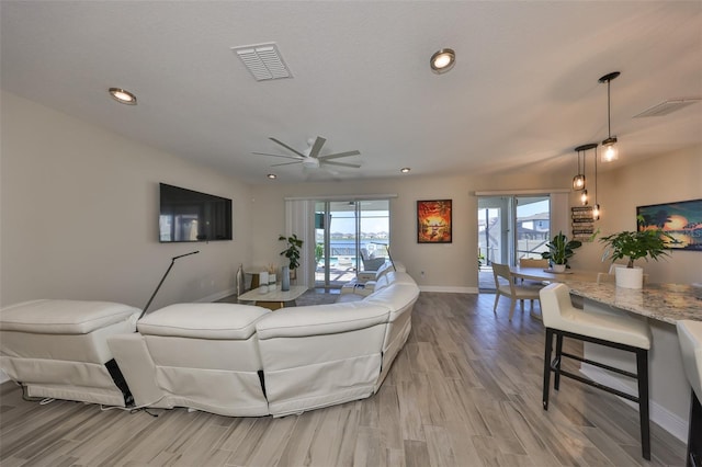 living room with recessed lighting, baseboards, visible vents, and light wood finished floors