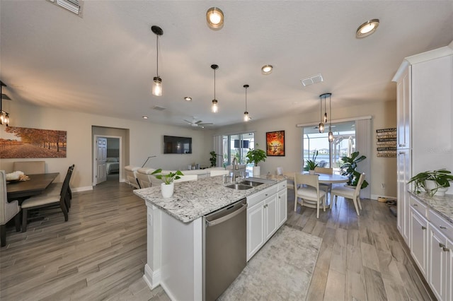 kitchen featuring a kitchen island with sink, light wood-style flooring, a sink, white cabinetry, and dishwasher