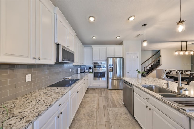 kitchen featuring tasteful backsplash, white cabinetry, stainless steel appliances, and a sink