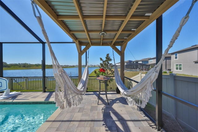 exterior space featuring glass enclosure, a water view, and a fenced in pool