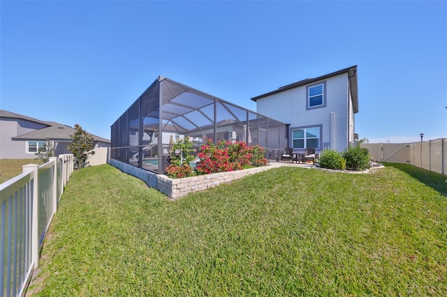 back of house featuring a patio, stucco siding, a lawn, a lanai, and a fenced backyard