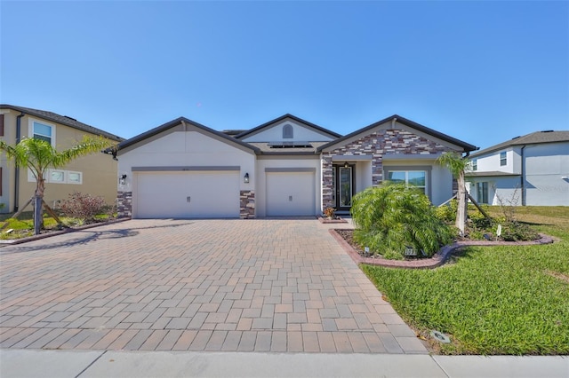 ranch-style home featuring stone siding, an attached garage, decorative driveway, roof mounted solar panels, and stucco siding