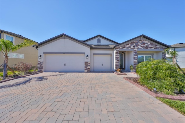 ranch-style house featuring an attached garage, stone siding, decorative driveway, and stucco siding