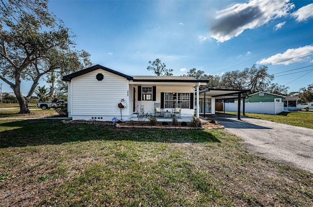 ranch-style home with a carport, covered porch, and a front yard