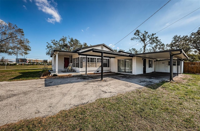 rear view of property with a carport, a yard, and a sunroom