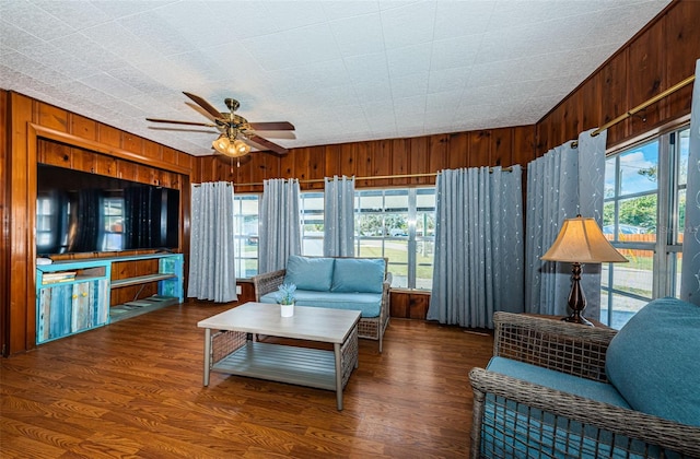 living room featuring dark hardwood / wood-style floors, wooden walls, and a wealth of natural light