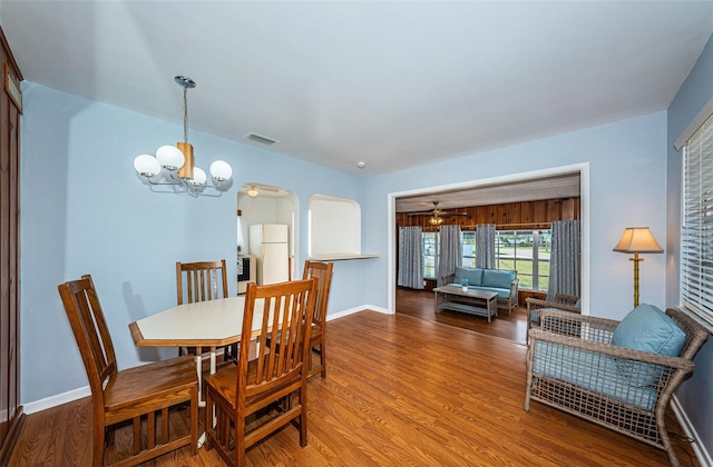 dining space with hardwood / wood-style floors and ceiling fan with notable chandelier