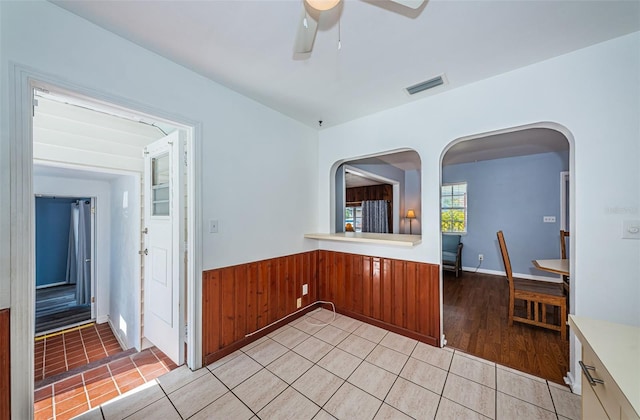 kitchen featuring light tile patterned floors, wooden walls, and ceiling fan