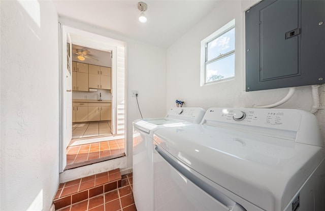 laundry area with washing machine and clothes dryer, electric panel, sink, and dark tile patterned floors