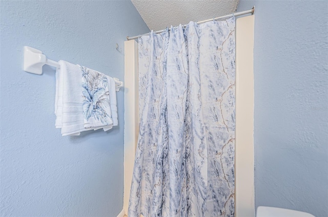 bathroom with toilet, a textured ceiling, and walk in shower