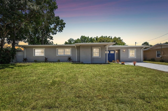 single story home with driveway, a front lawn, and stucco siding