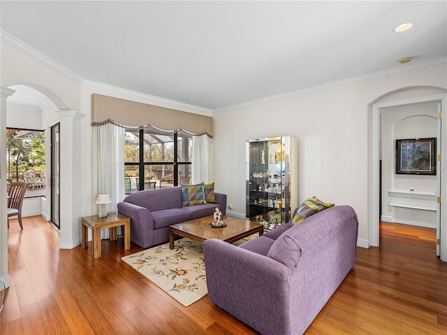 living room featuring hardwood / wood-style flooring, crown molding, and decorative columns