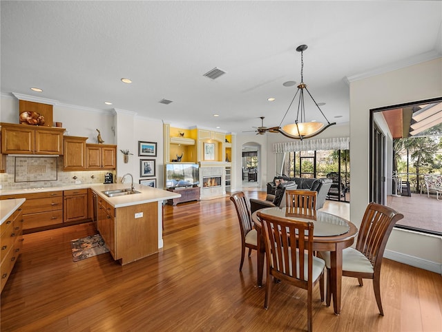 dining room featuring ornamental molding, wood-type flooring, a fireplace, and sink