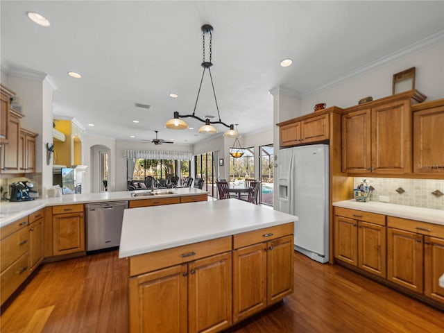 kitchen featuring sink, hanging light fixtures, white refrigerator with ice dispenser, stainless steel dishwasher, and kitchen peninsula