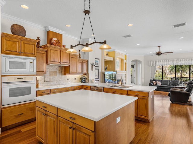 kitchen with a kitchen island, decorative light fixtures, sink, white appliances, and light wood-type flooring