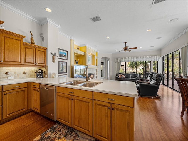 kitchen with sink, crown molding, dark wood-type flooring, dishwasher, and kitchen peninsula