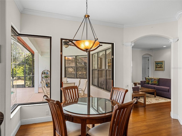 dining area with crown molding, light hardwood / wood-style floors, and decorative columns