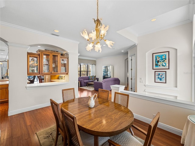 dining space with a notable chandelier, crown molding, wood-type flooring, and ornate columns