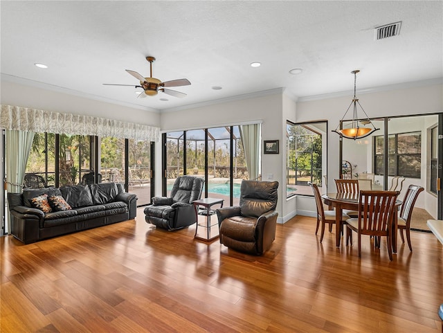 living room featuring hardwood / wood-style floors, a textured ceiling, ornamental molding, and ceiling fan