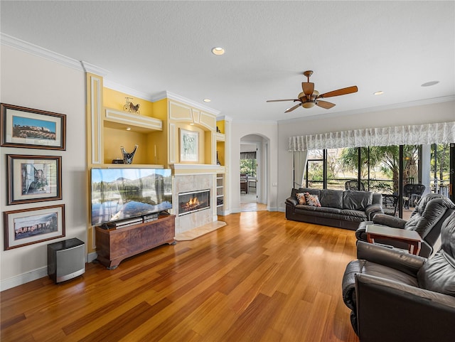 living room featuring hardwood / wood-style flooring, ornamental molding, a tile fireplace, and a wealth of natural light