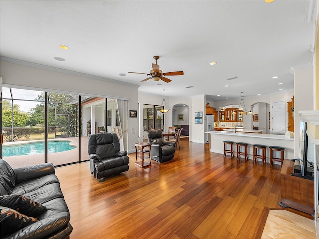 living room featuring ceiling fan, ornamental molding, and light hardwood / wood-style flooring